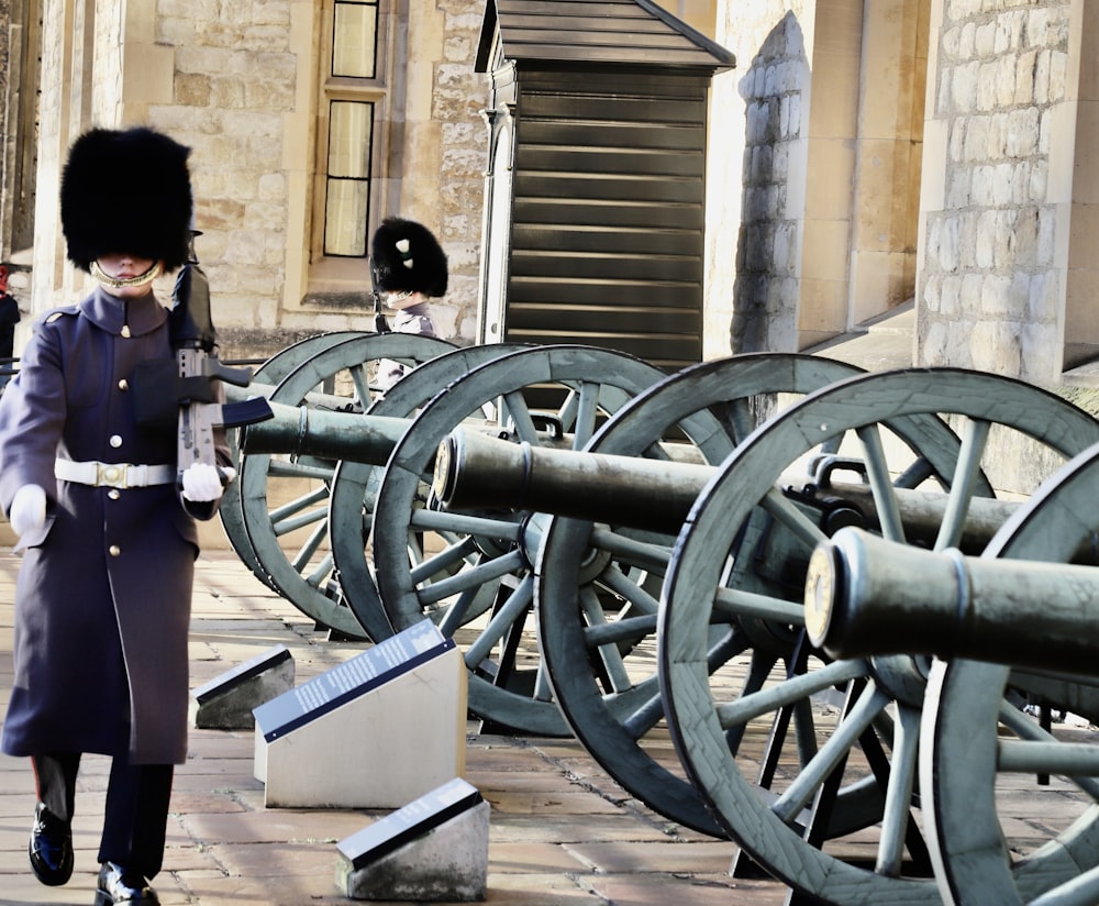a man in uniform standing next to a row of cannon wheels