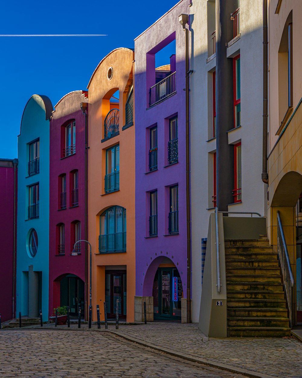 a row of multicolored buildings on a cobblestone street
