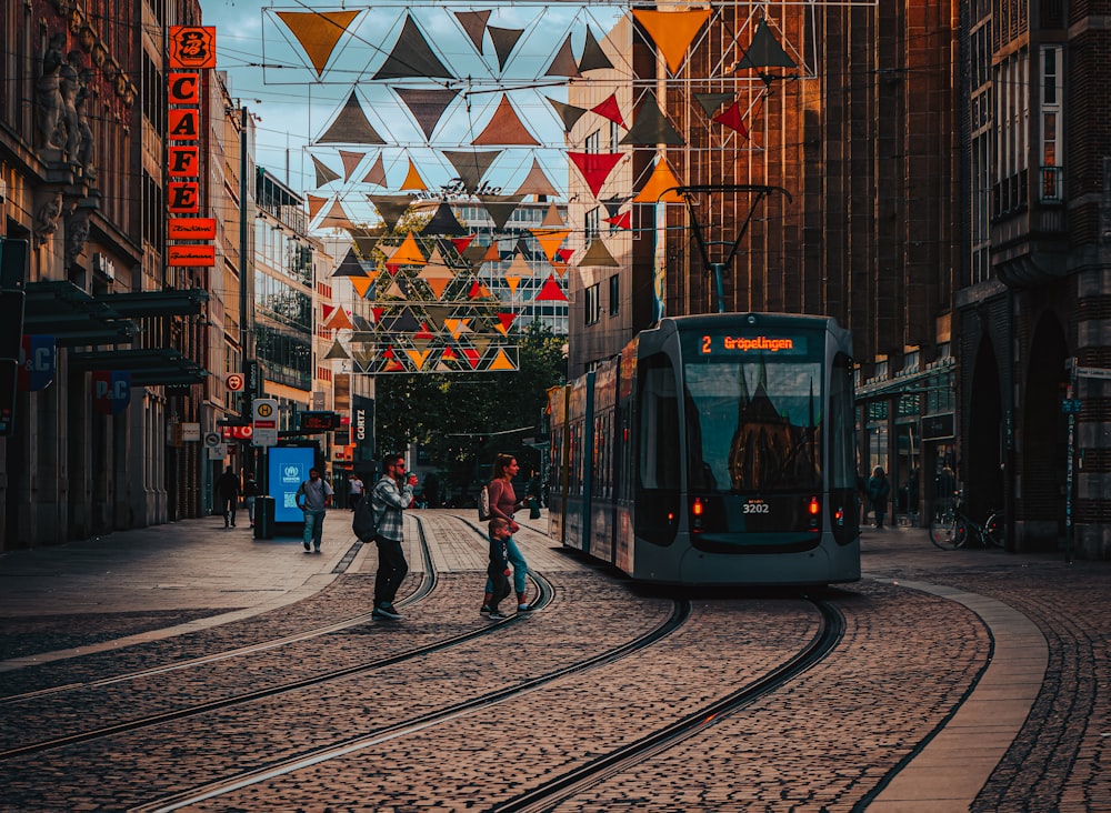 two people walking on a cobblestone street next to a train