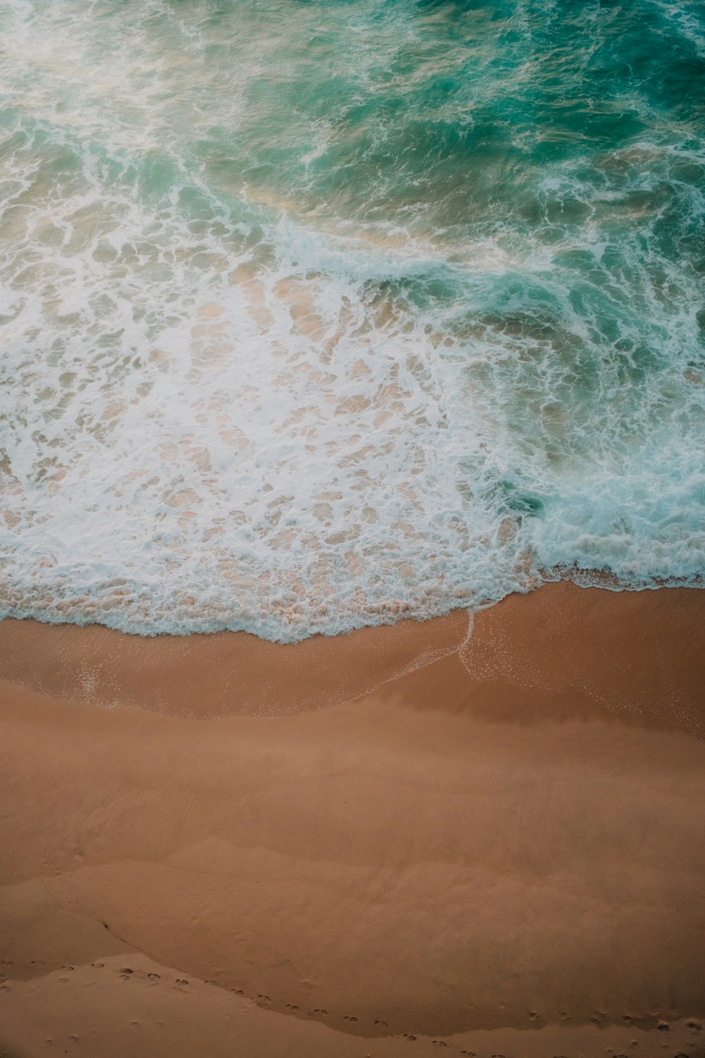 an aerial view of a beach with waves coming in