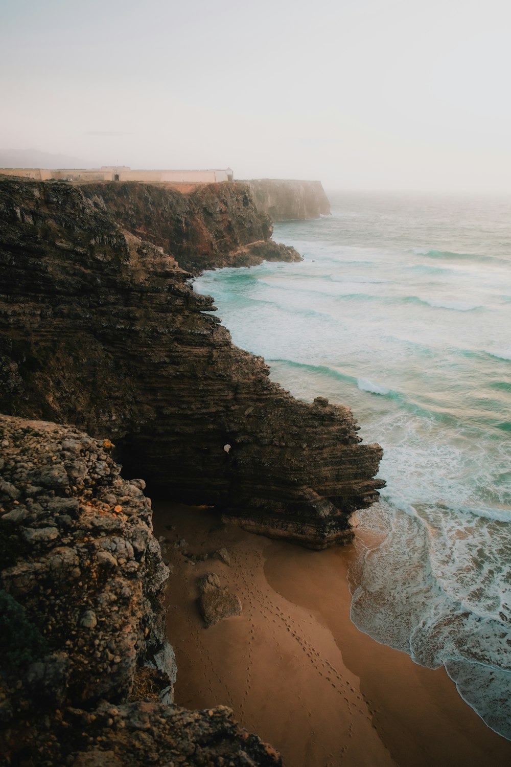 a beach with a cliff and a body of water