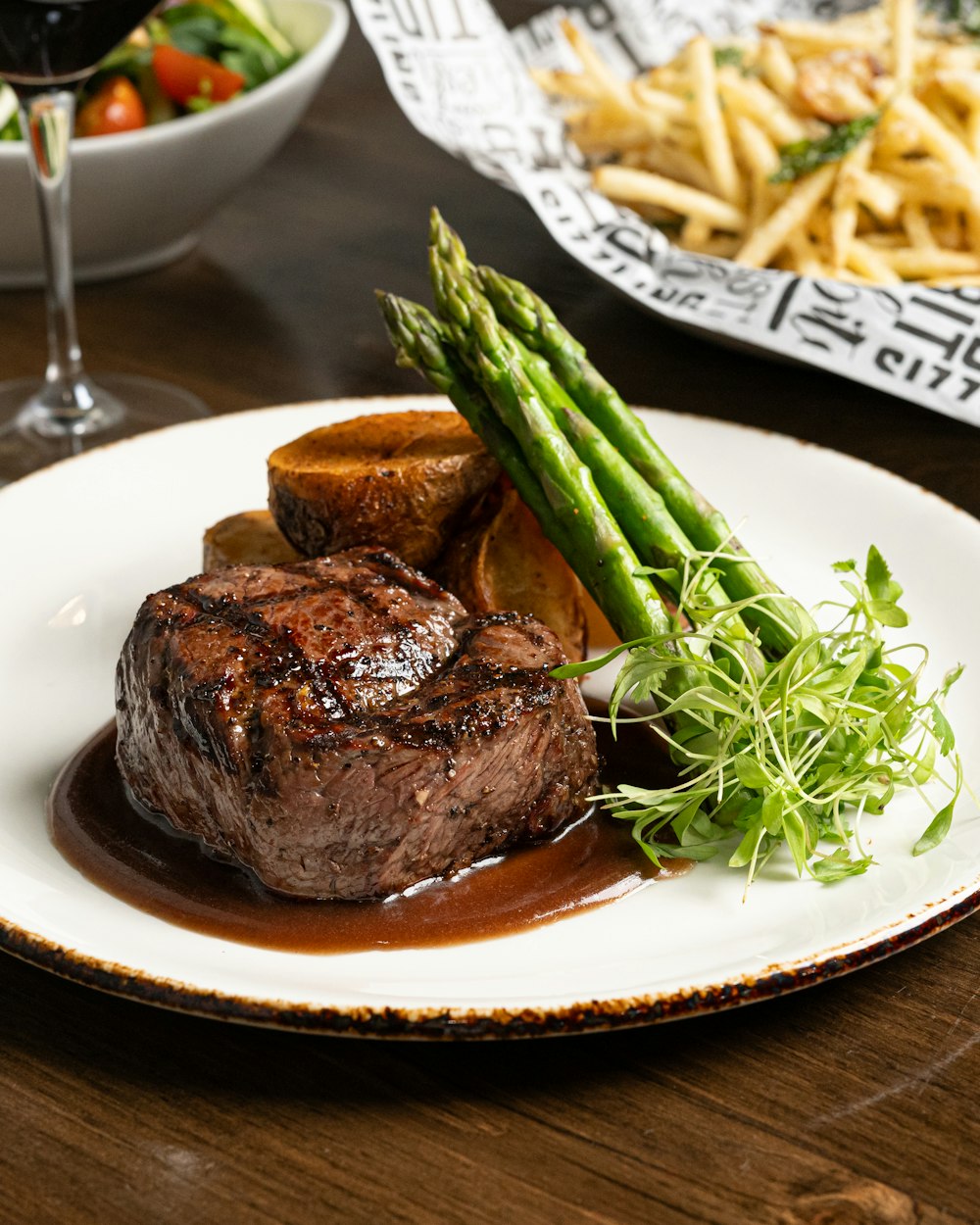 a plate of steak and asparagus with a glass of wine