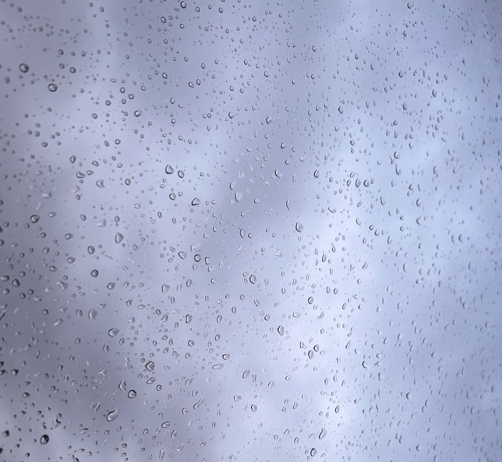 rain drops on a window with a cloudy sky in the background