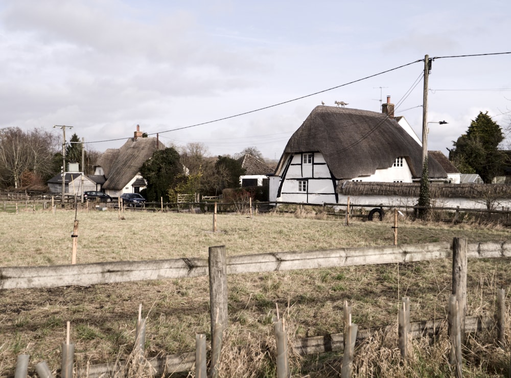 a farm with a thatched roof and a fence