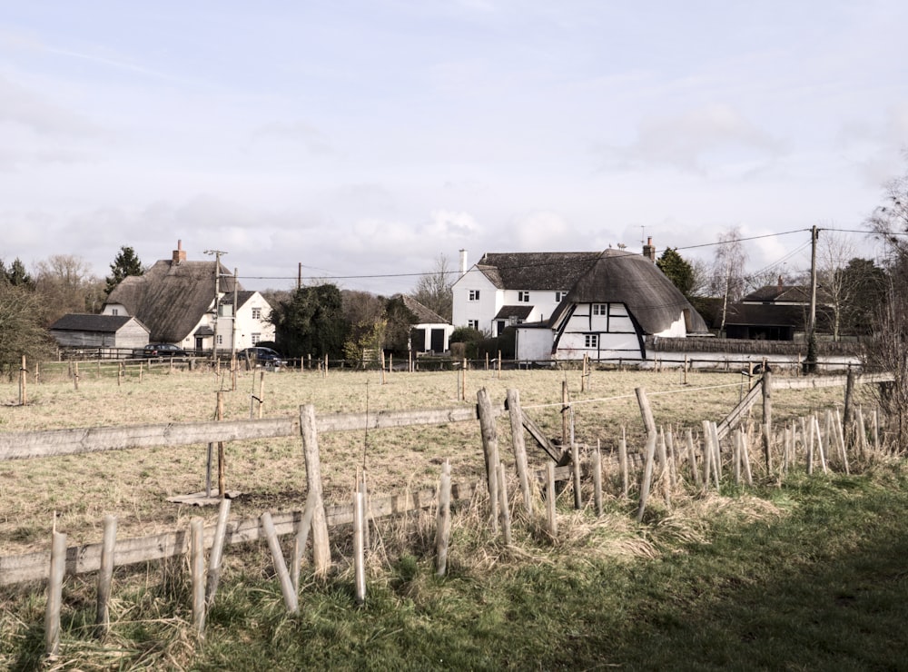 a farm house with a thatched roof and a wooden fence