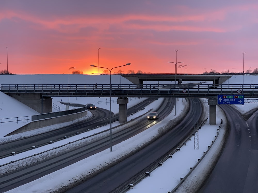 the sun is setting over a snowy highway