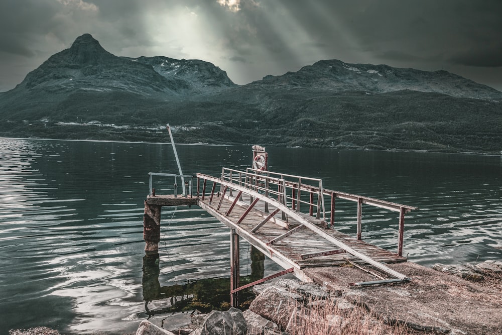 un molo di legno seduto in cima a un lago sotto un cielo nuvoloso