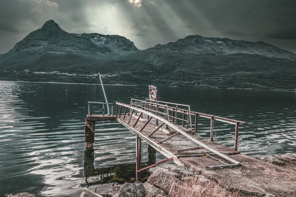 a wooden dock sitting on top of a lake under a cloudy sky