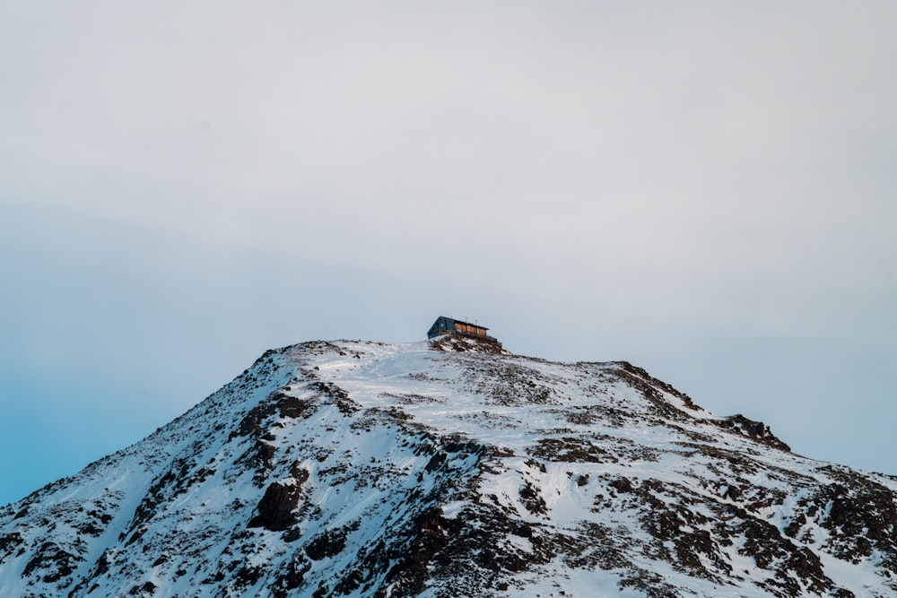 a snow covered mountain with a house on top of it