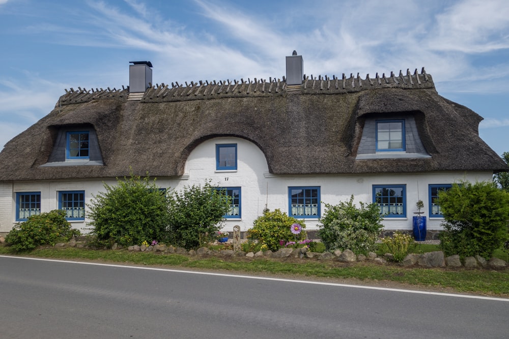 a white house with a thatched roof and blue windows