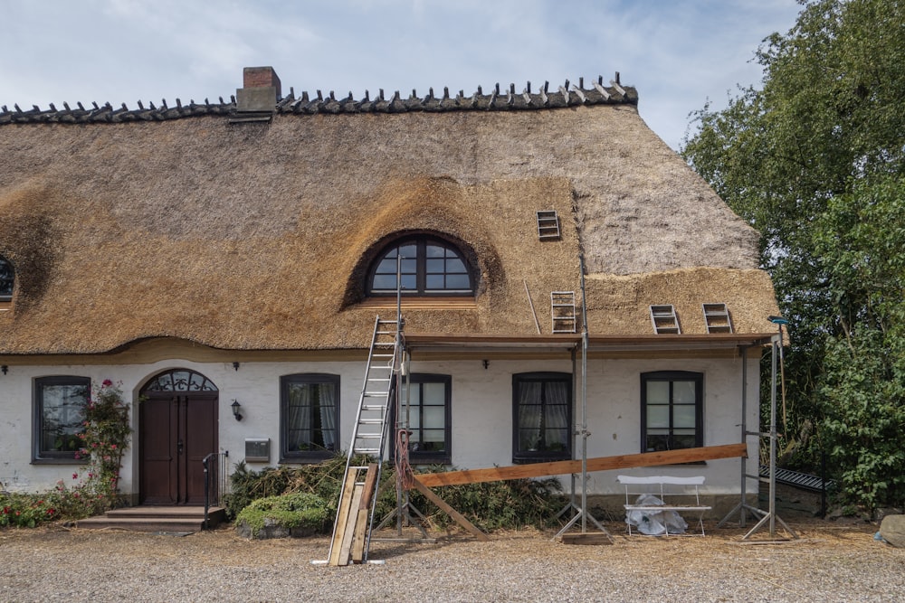 une maison avec un toit de chaume et une échelle