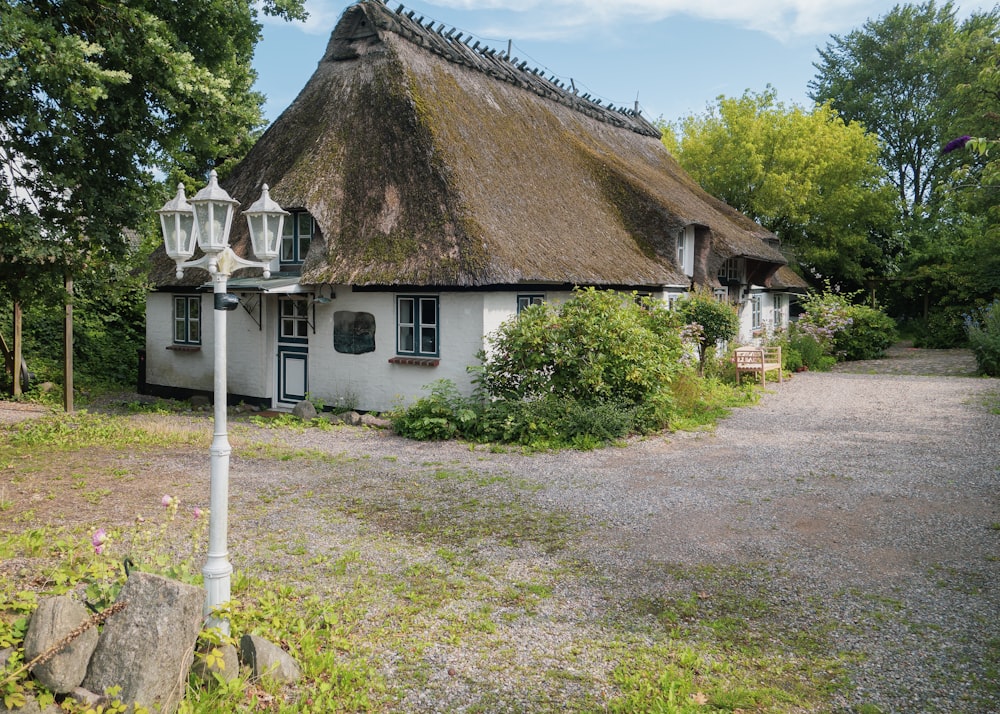 a white house with a thatched roof in a wooded area