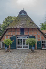 a brick building with a thatched roof and green shutters