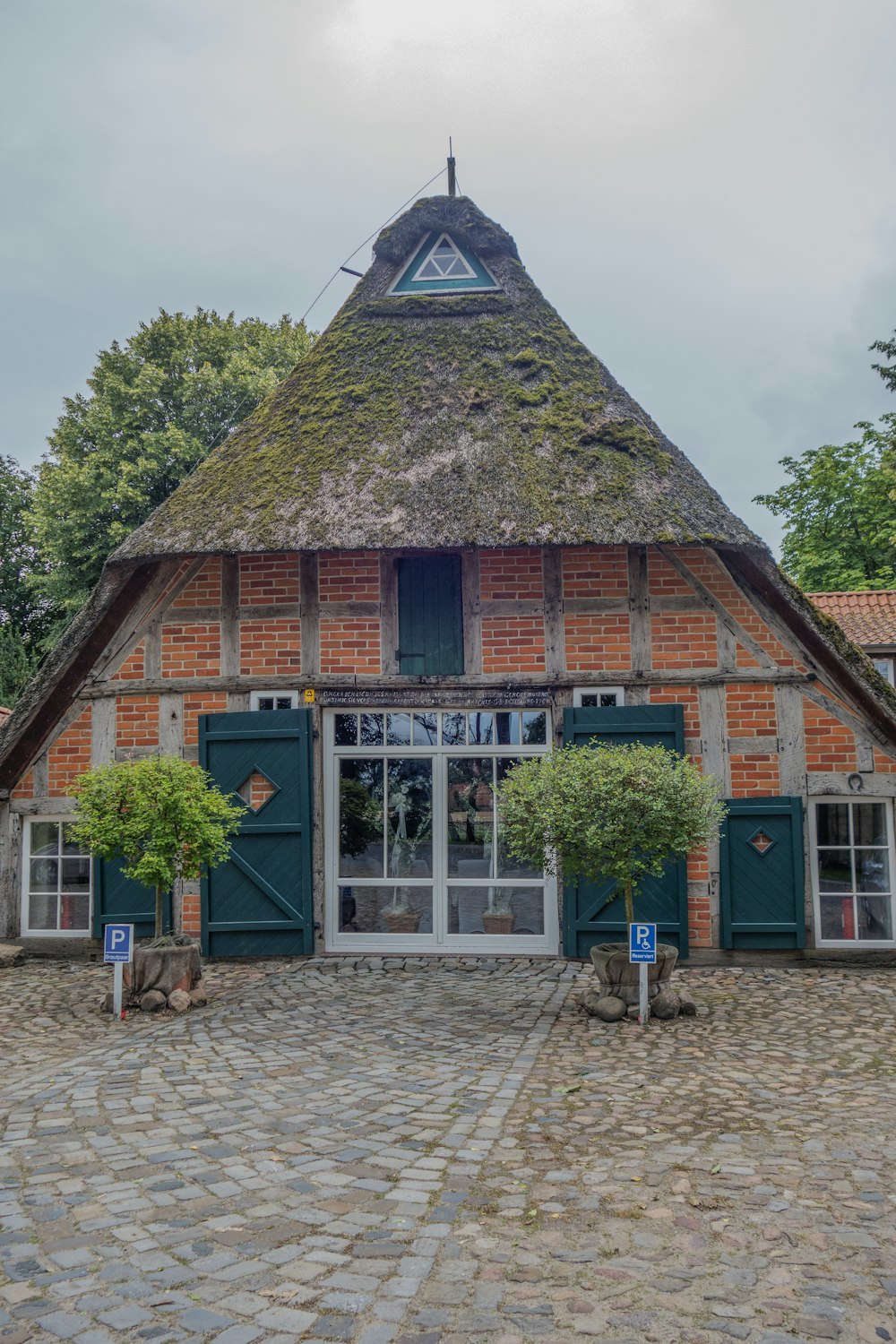 a brick building with a thatched roof and green shutters