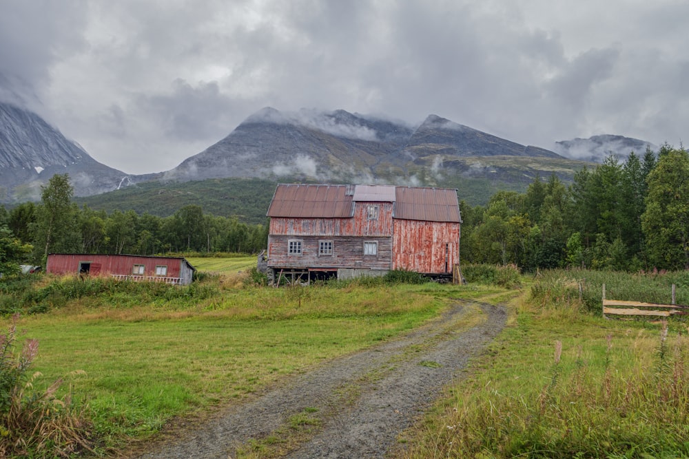 an old barn in a field with mountains in the background