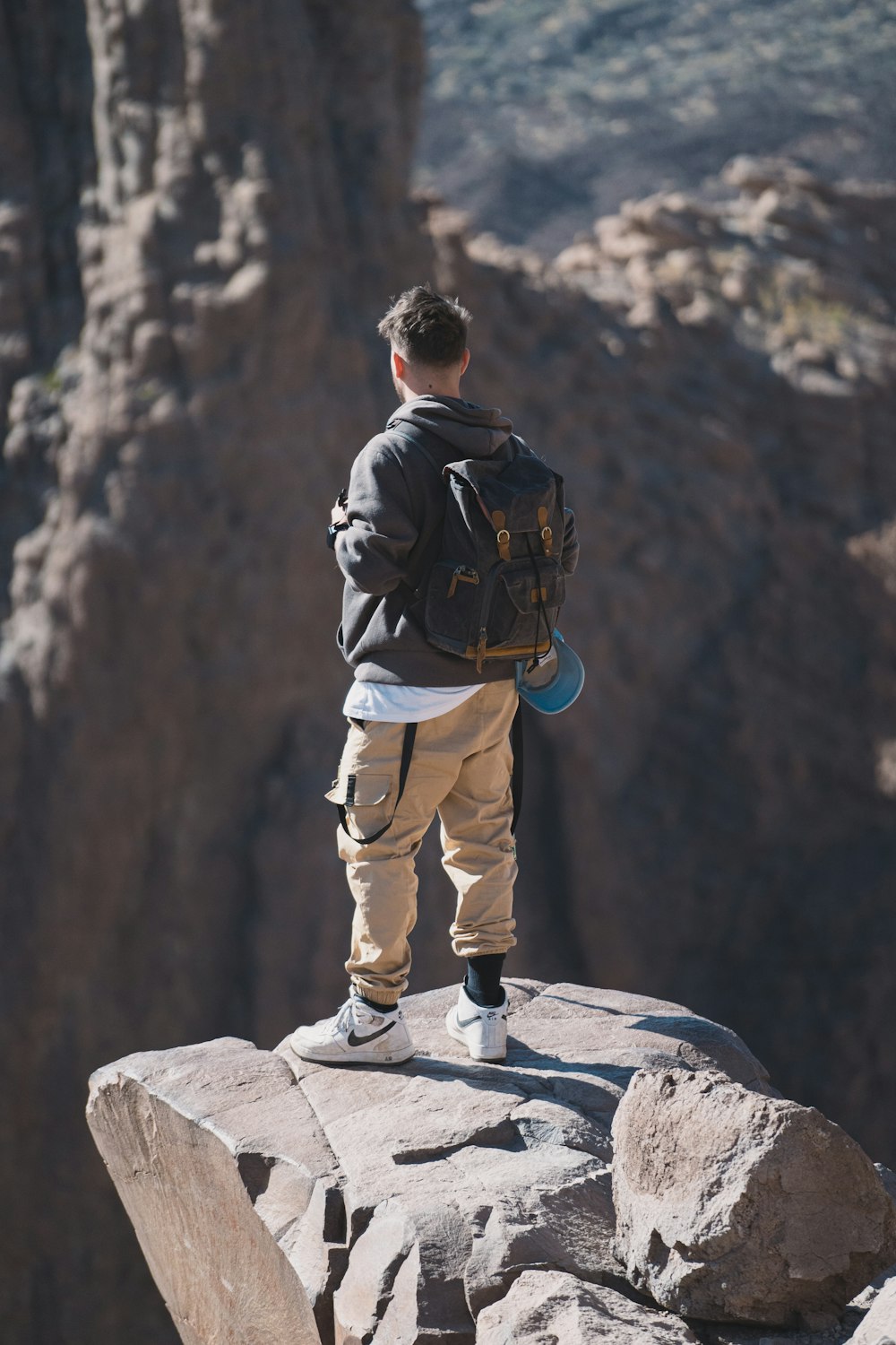 a young man standing on top of a large rock