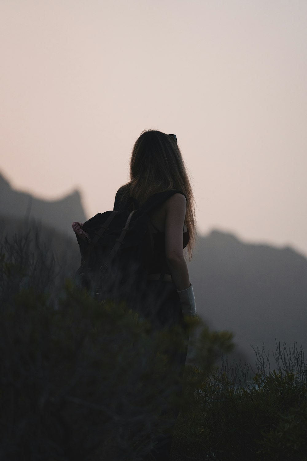 a woman with a backpack standing on top of a hill