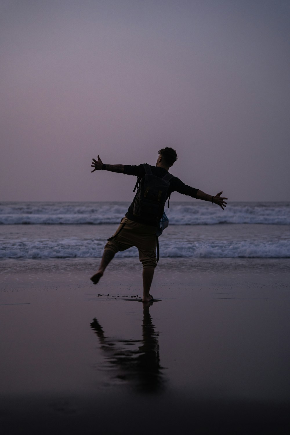 a man standing on top of a beach next to the ocean