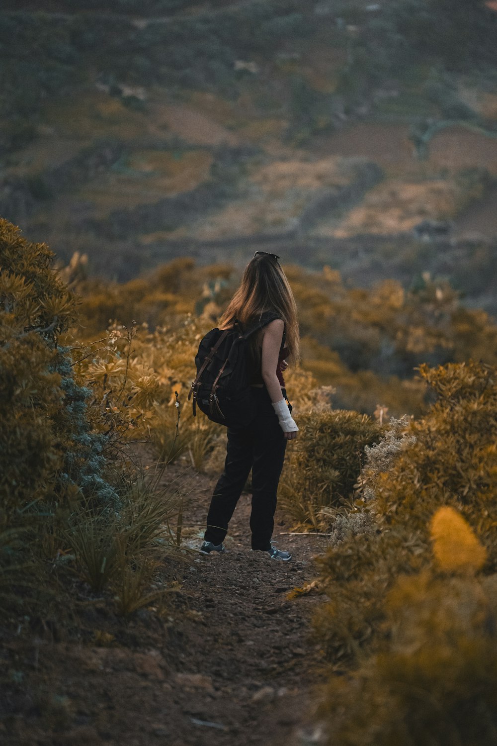 a woman with a back pack walking up a hill