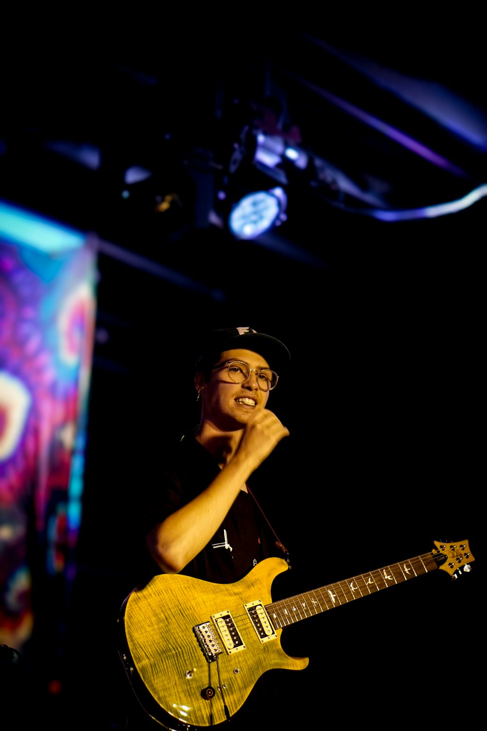 a man holding a yellow guitar in his right hand
