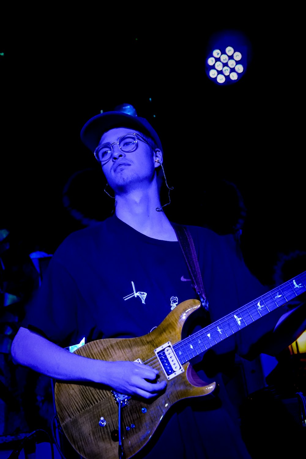 un homme avec un chapeau et des lunettes jouant de la guitare