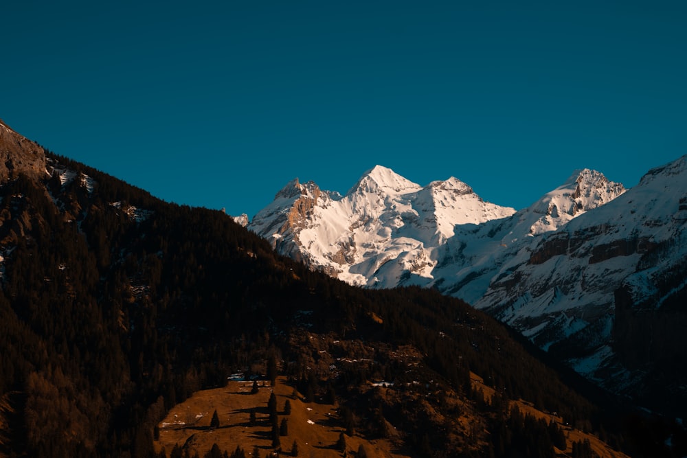 a snowy mountain range with a house in the foreground