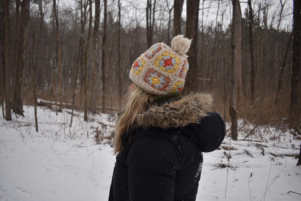 a woman standing in the snow wearing a hat