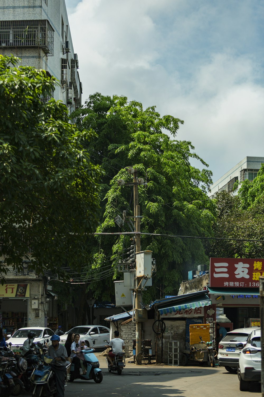 a city street with cars and motorcycles parked on the side of the road