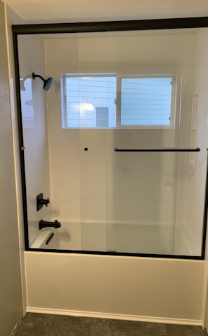 a bathroom with a glass shower door and tile floor