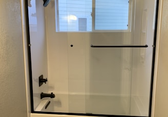 a bathroom with a glass shower door and tile floor