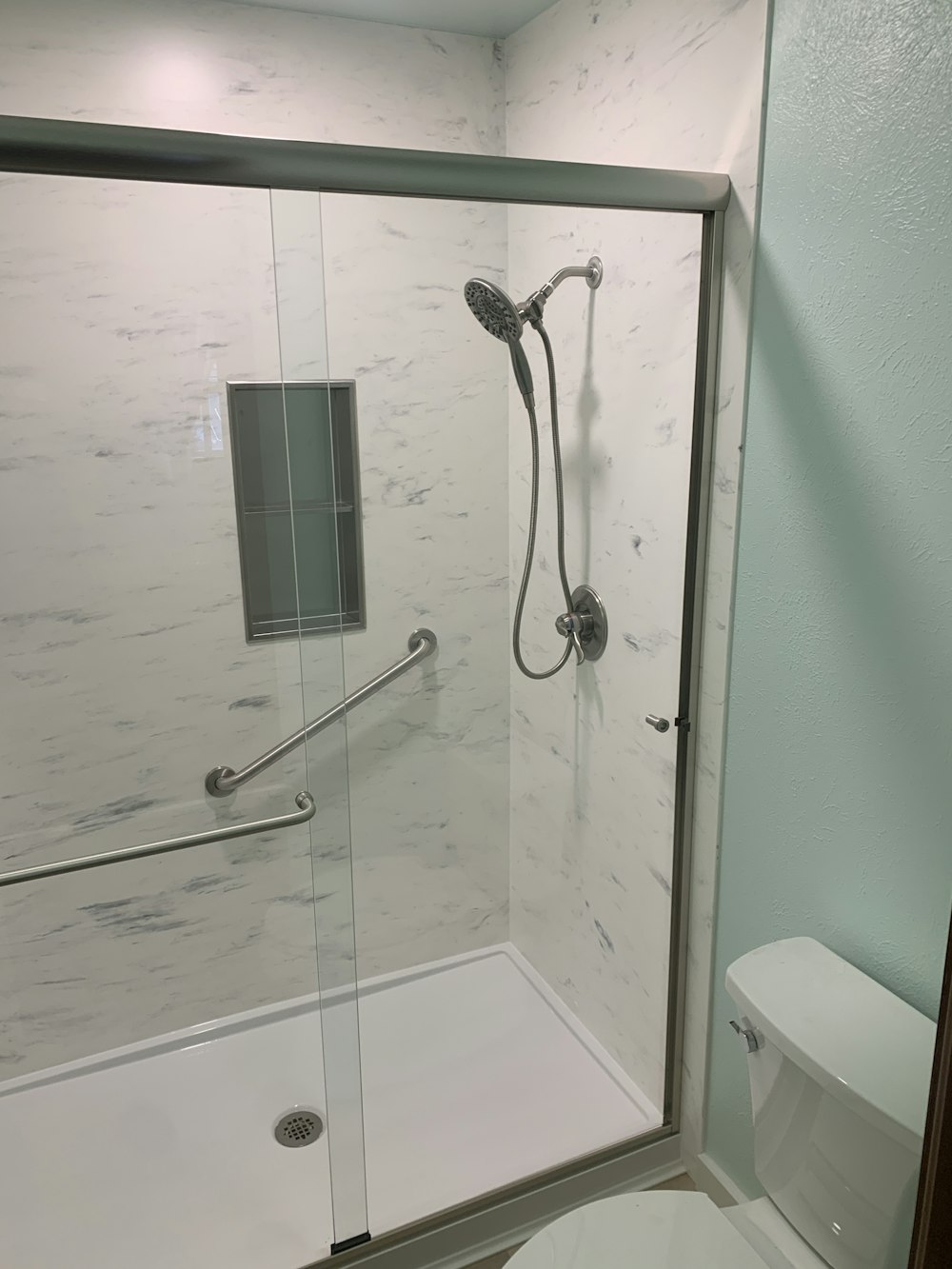 a bathroom with a glass shower door and a toilet