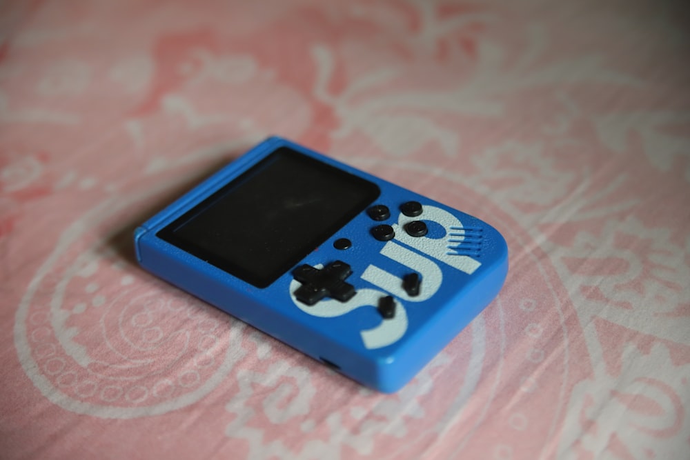 a blue gameboy sitting on top of a bed