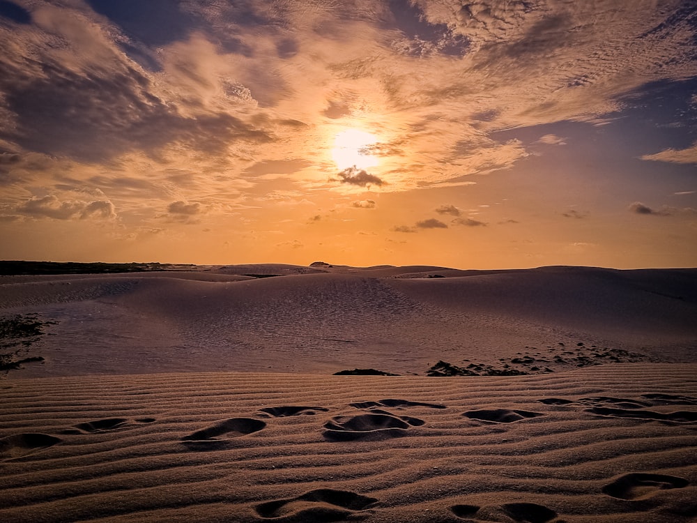 the sun is setting over the sand dunes