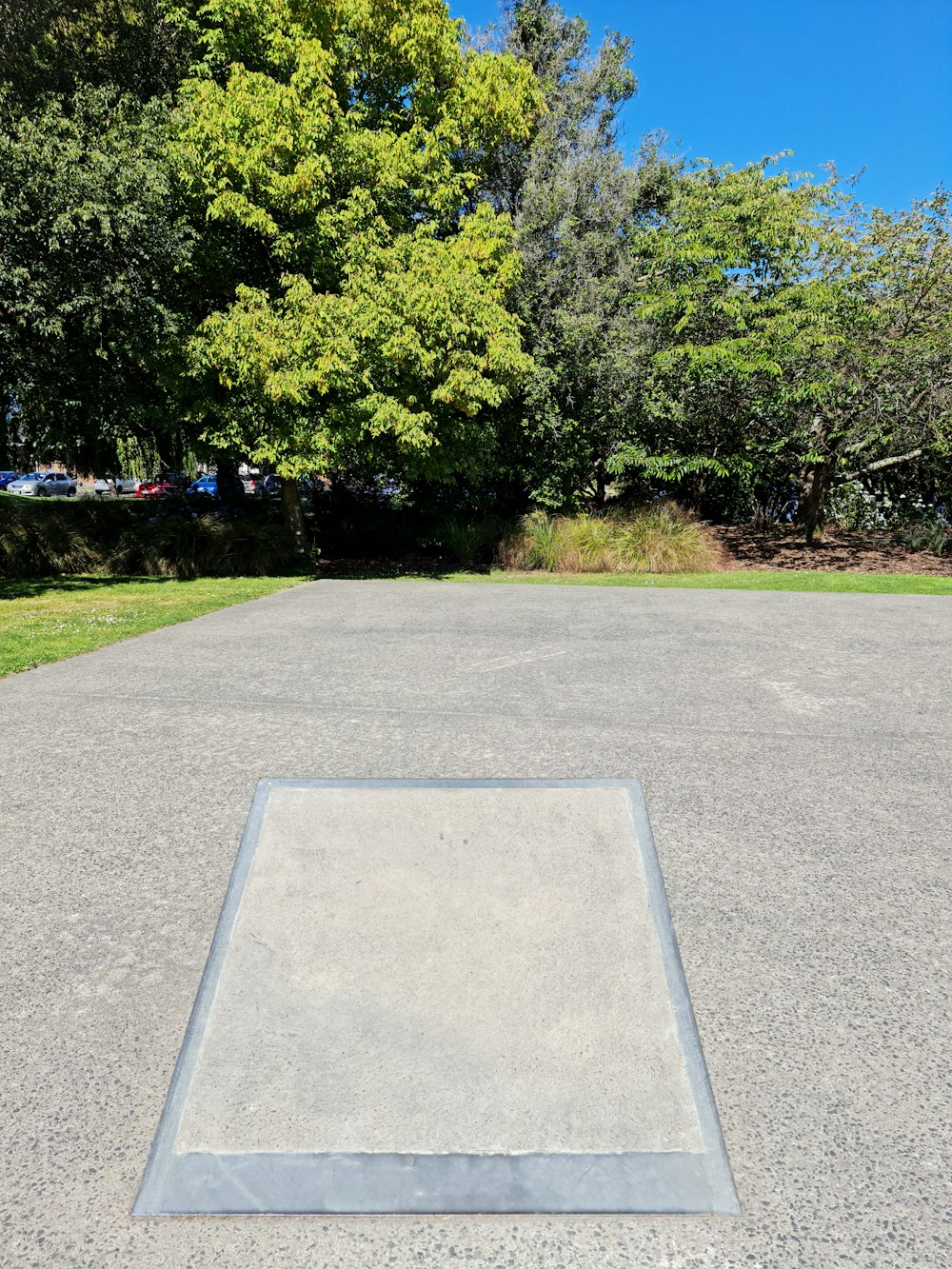 an empty parking lot with trees in the background