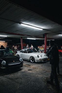 a man standing next to a white car in a parking lot