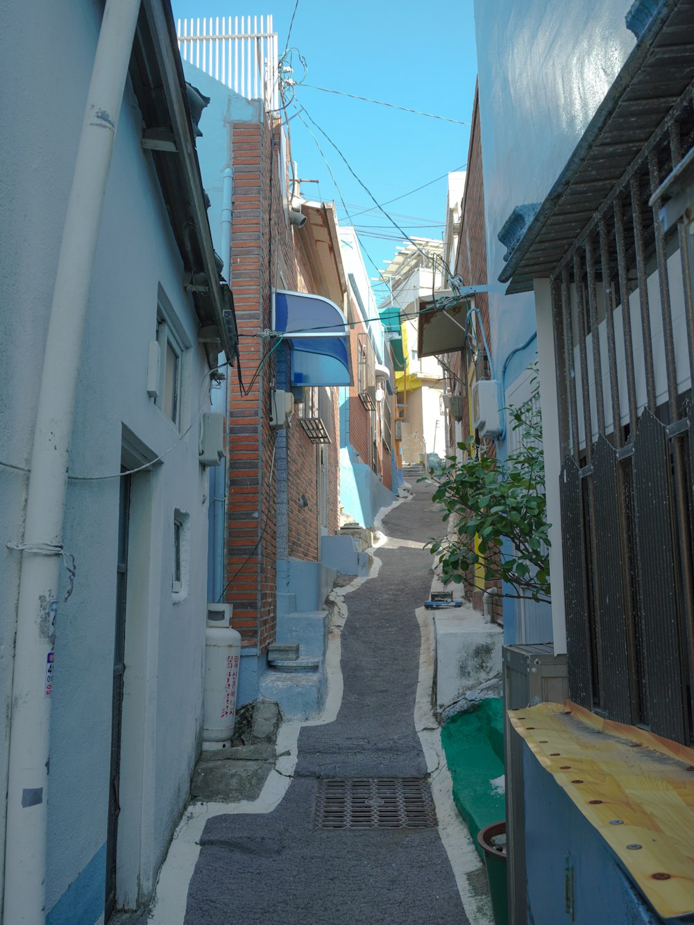 a narrow alleyway with a blue building and a blue and white awning