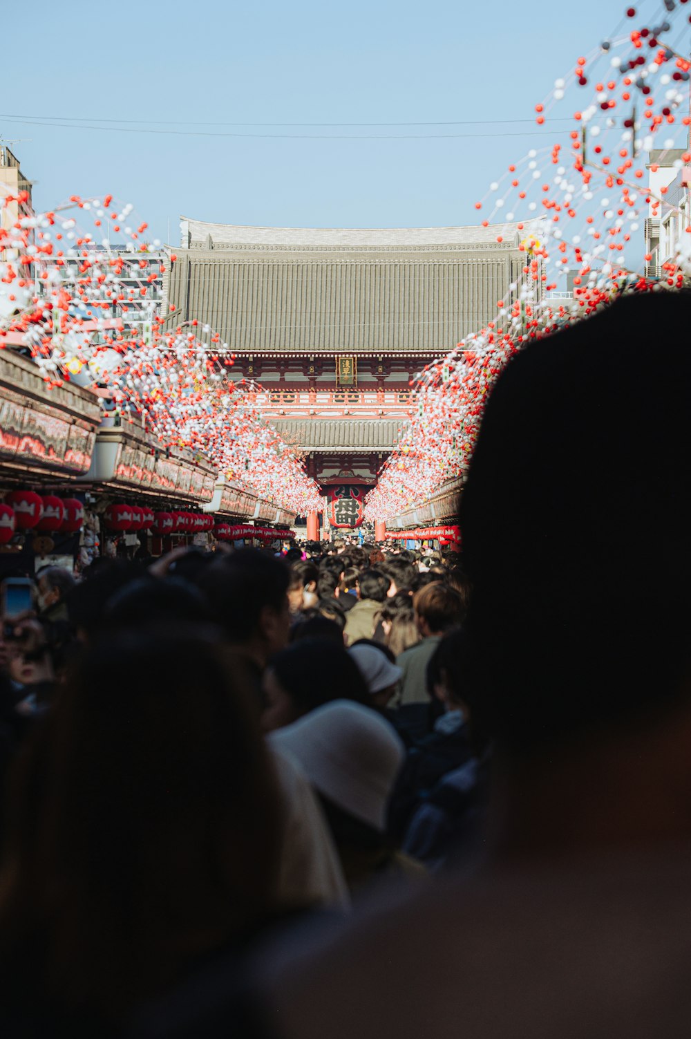 a crowd of people walking down a street under a blue sky