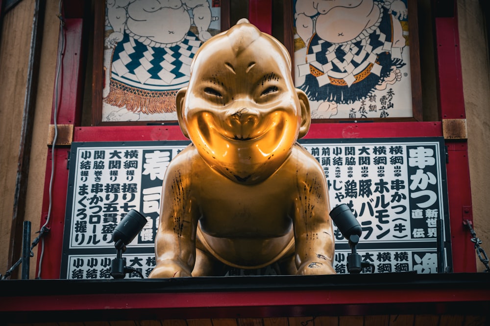 una estatua dorada de una persona con una sonrisa en la cara