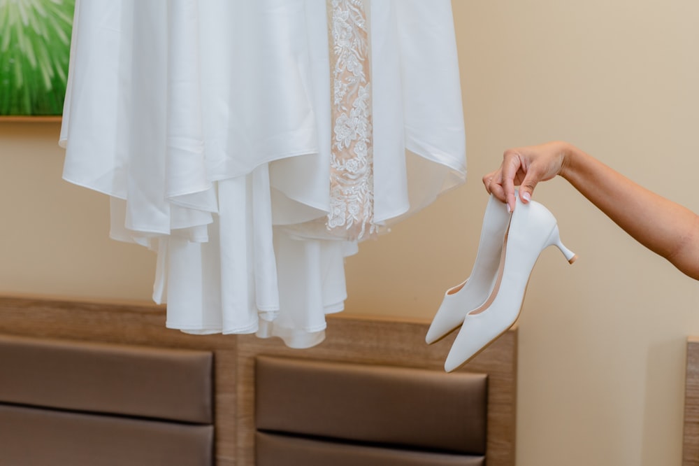 a woman holding a pair of white high heels