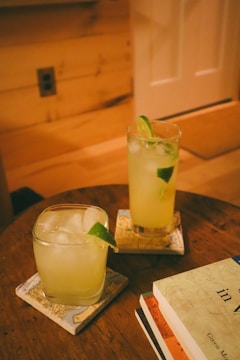 a wooden table topped with two glasses filled with drinks
