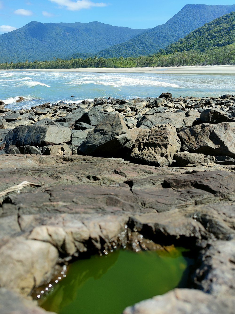 a green pool of water surrounded by rocks