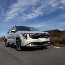 a white car driving down a road under a blue sky