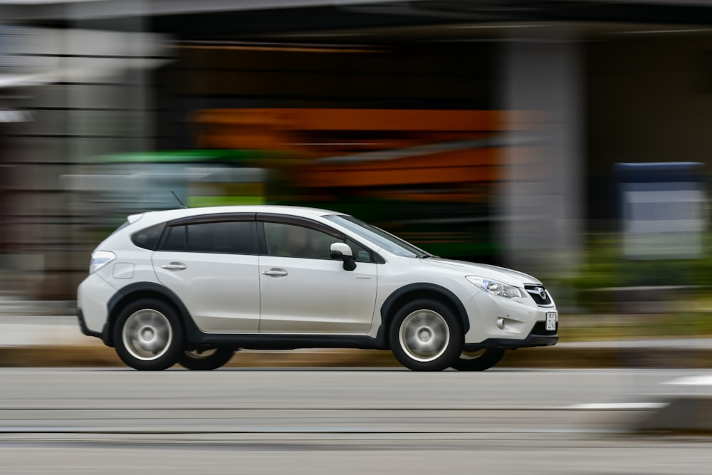 a white car driving down a street next to a building