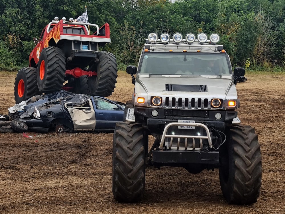 ein Auto, das neben einem Monstertruck im Dreck sitzt