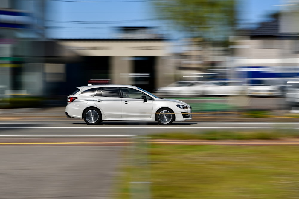 a white car driving down a street next to tall buildings