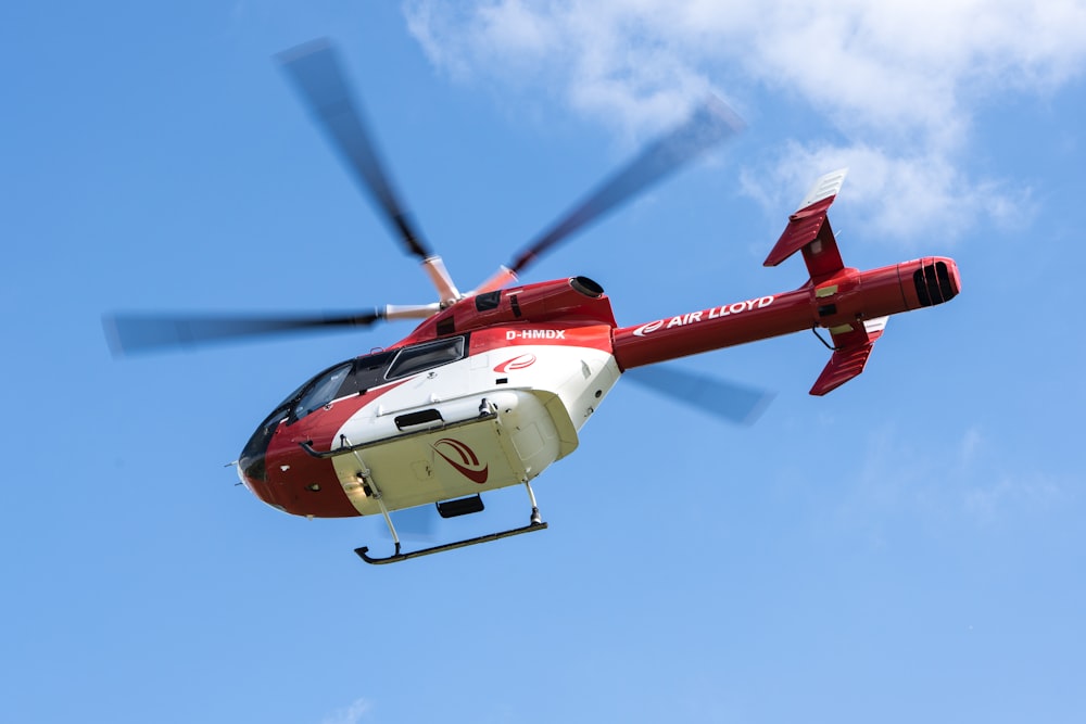 青空を飛ぶ赤と白のヘリコプター