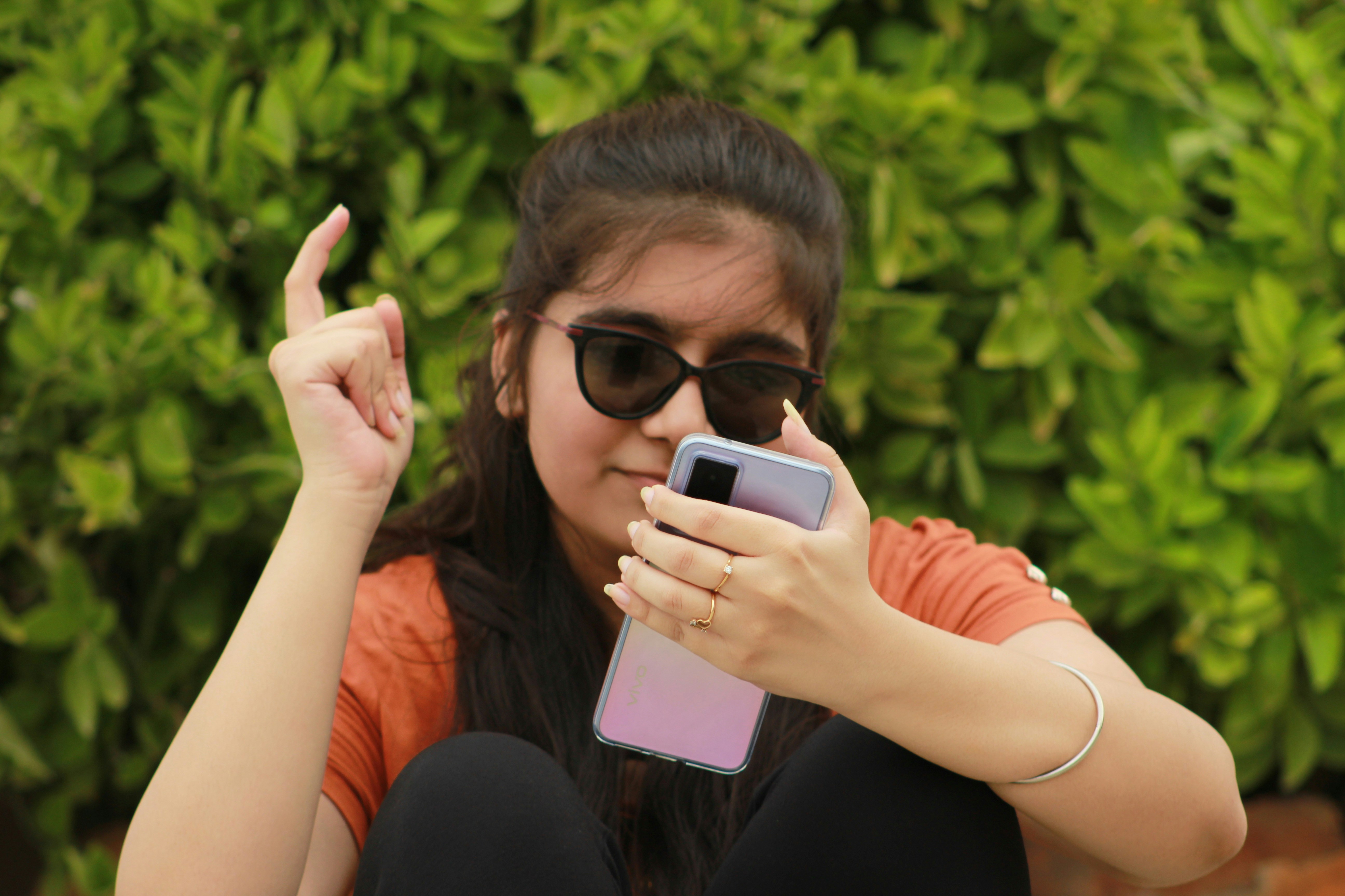 a woman sitting on the ground holding a cell phone