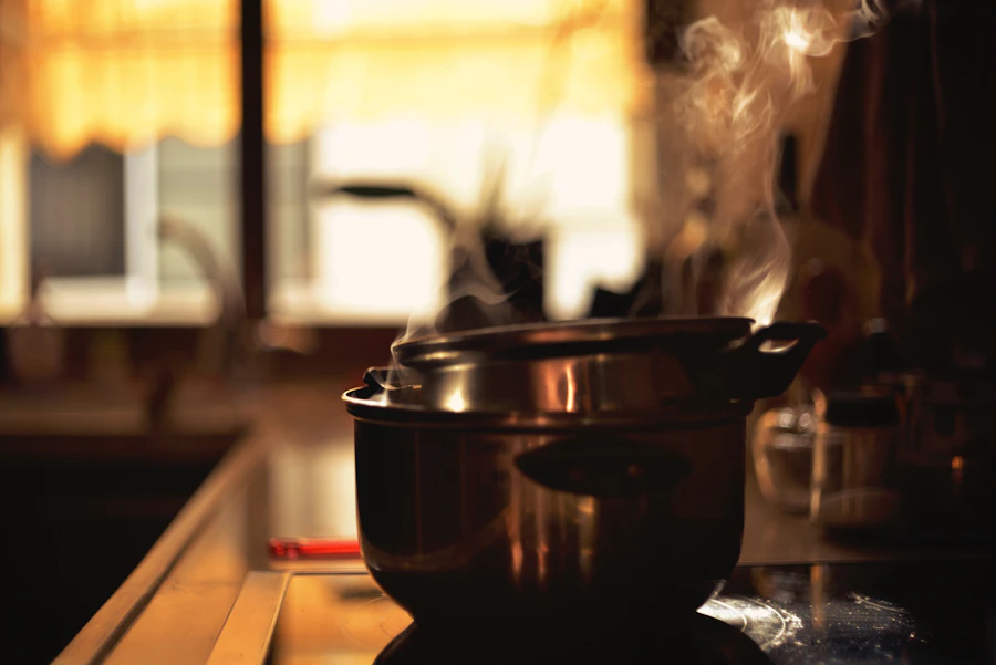 A pot on the stove with steam rising, in a dim, warm home kitchen
