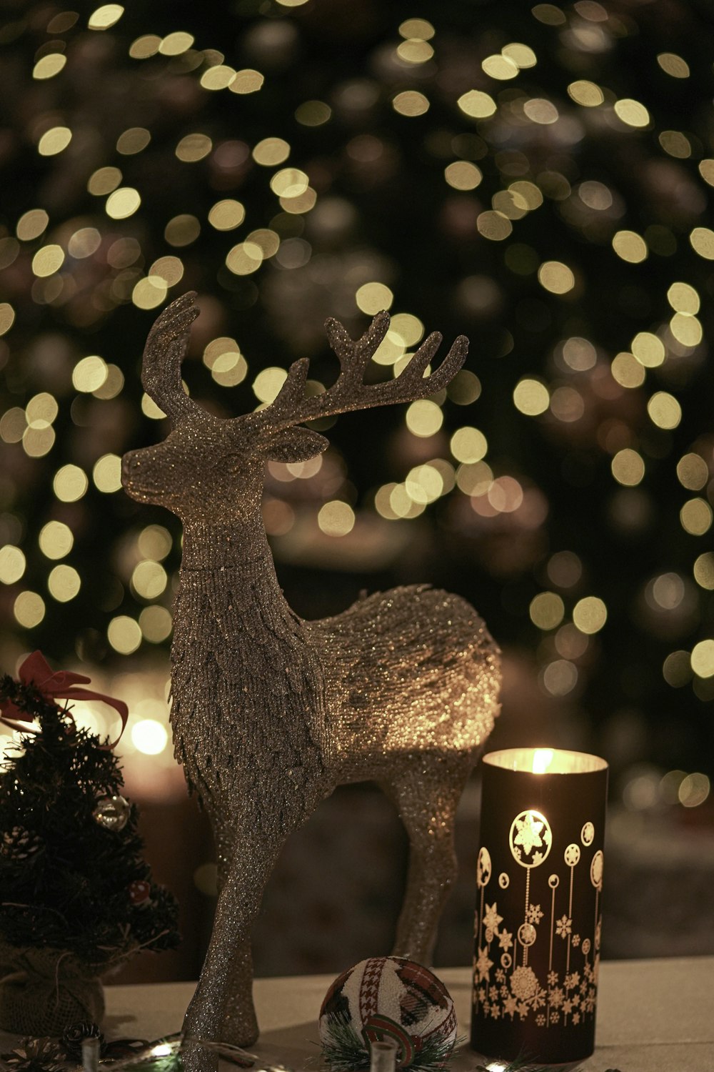 a deer statue next to a candle and a christmas tree