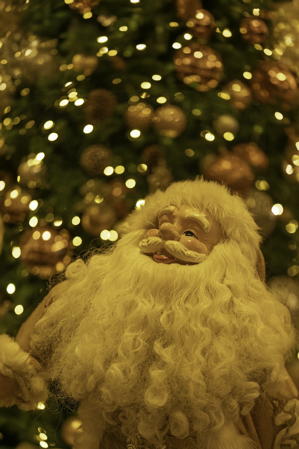 a close up of a santa clause near a christmas tree